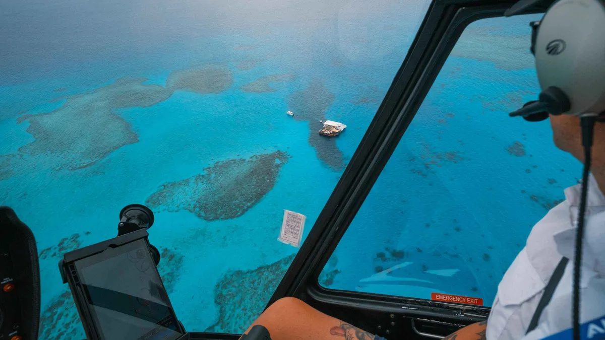 View from the helicopter cockpit over the turquoise reefs and islands on the Mamanuca scenic flight from Denarau