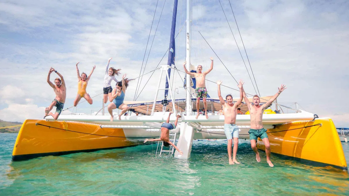 Passengers jumping off the yellow Sabre sailing catamaran during the South Sea sailing day in the Mamanuca Islands